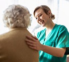 Nurse in scrubs holding her hand on patients back